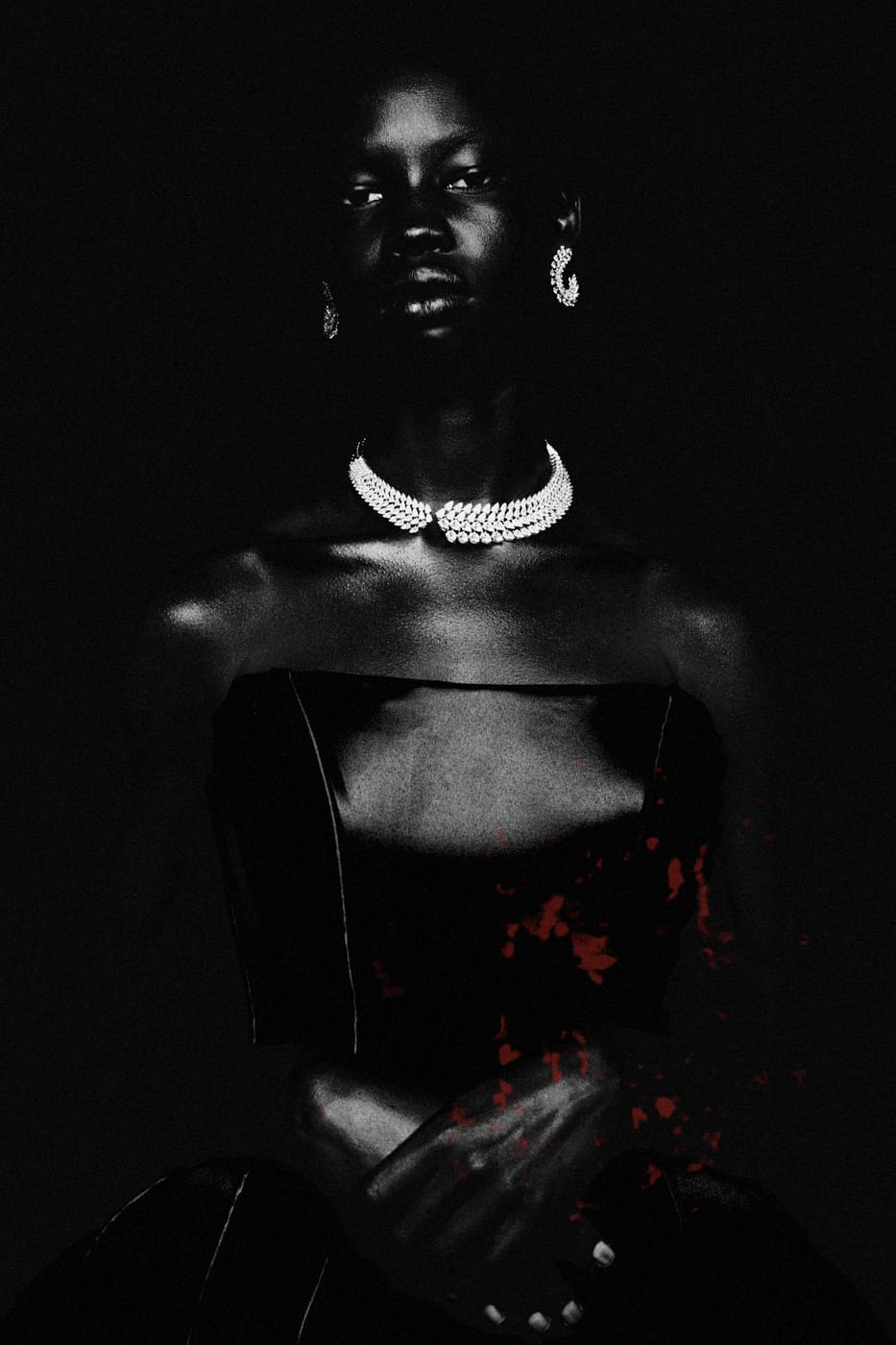 A model in a strapless black bodice and pearl collar, red paint spattered across the front