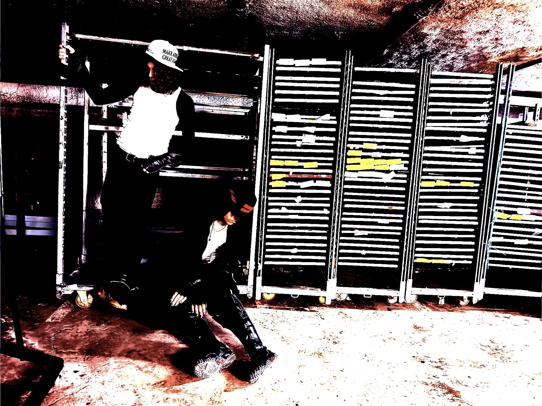 A blown-out flash frame in a stockroom, one figure pinned against the shelving