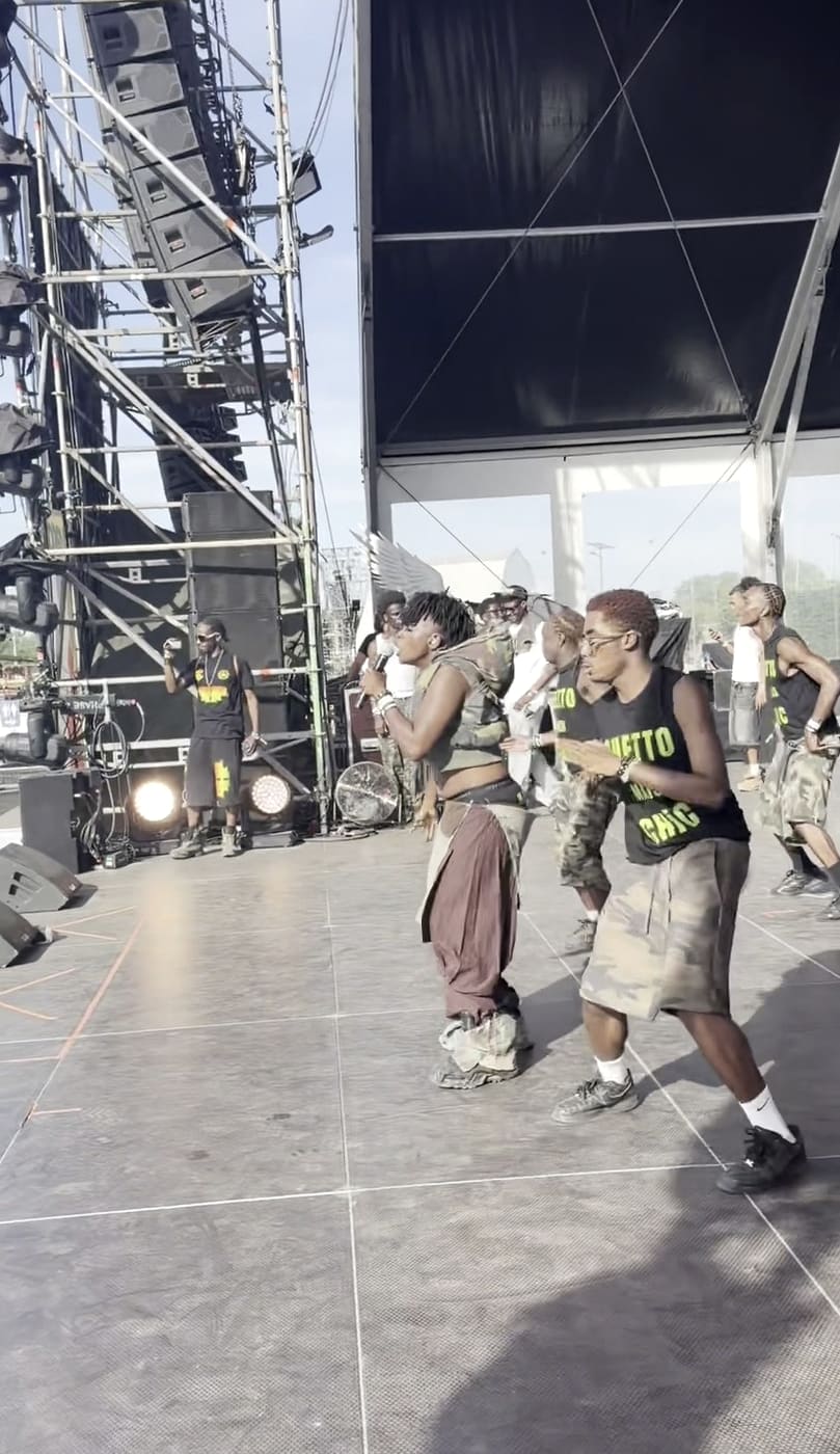 Ezek at the mic on the Yardland main stage, dancers moving behind her