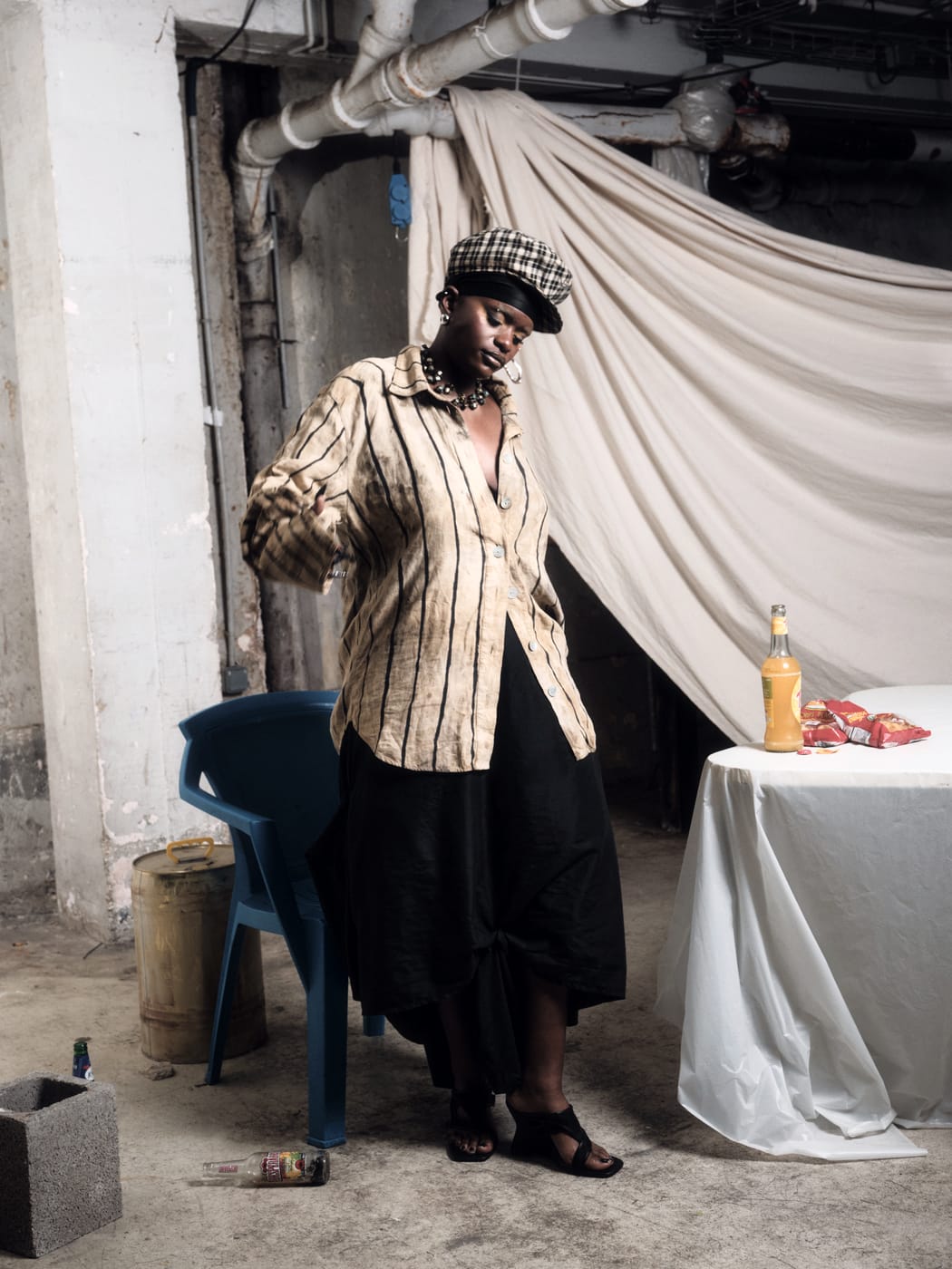 Ezek standing at the dressed table in a check beret and striped shirt, a bottle of Fanta on the cloth