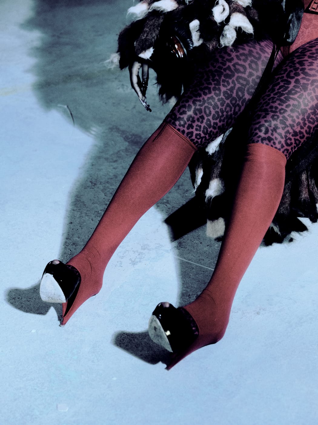 Her legs in red tights and leopard print, stretched from the armchair across the blue floor