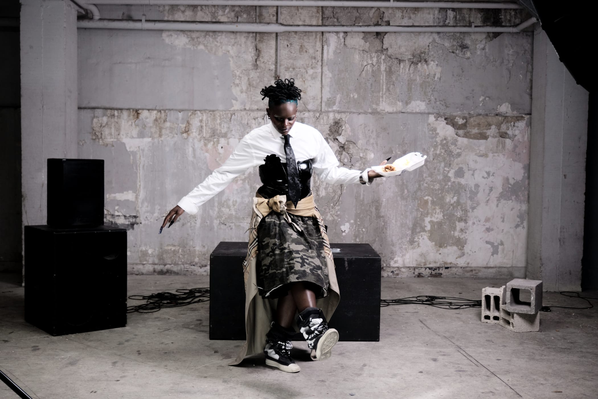 Ezek moving between the speakers, the white pipe in one hand, arms out