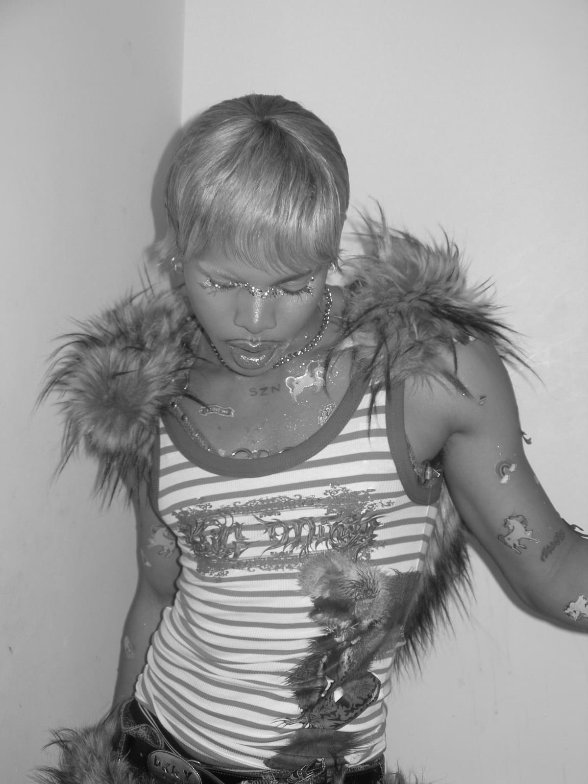 Oluwa.MP4 standing, eyes down, faux fur on his shoulders