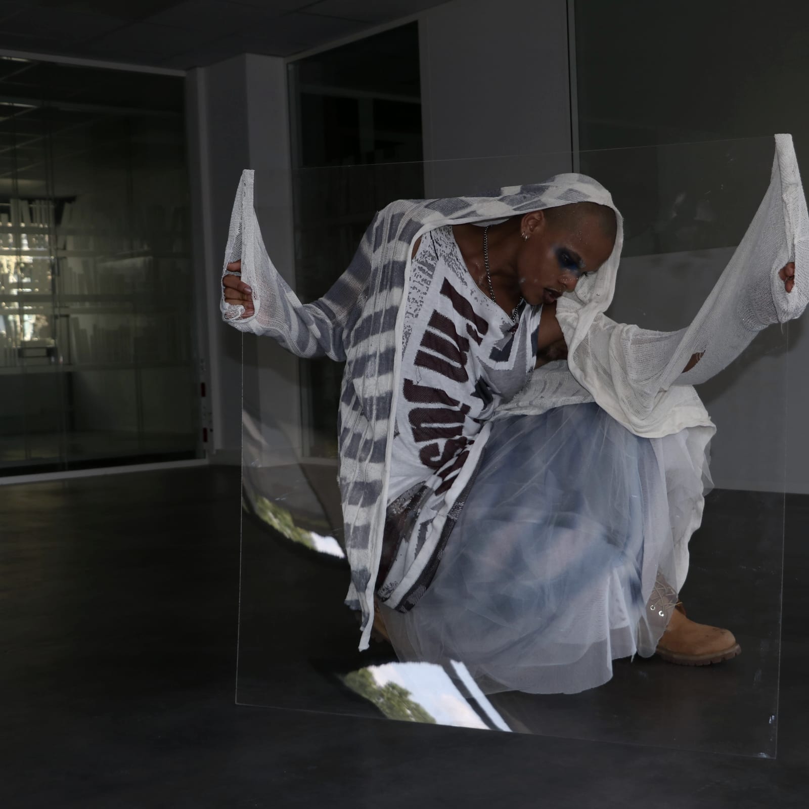 Oluwa crouched behind the pane, both shawl ends raised