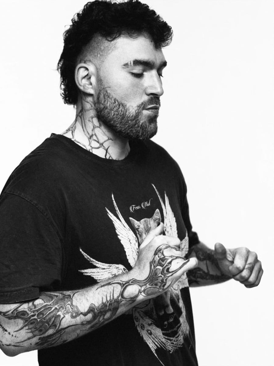 TWONSKi in profile, eyes closed, tattooed hands raised