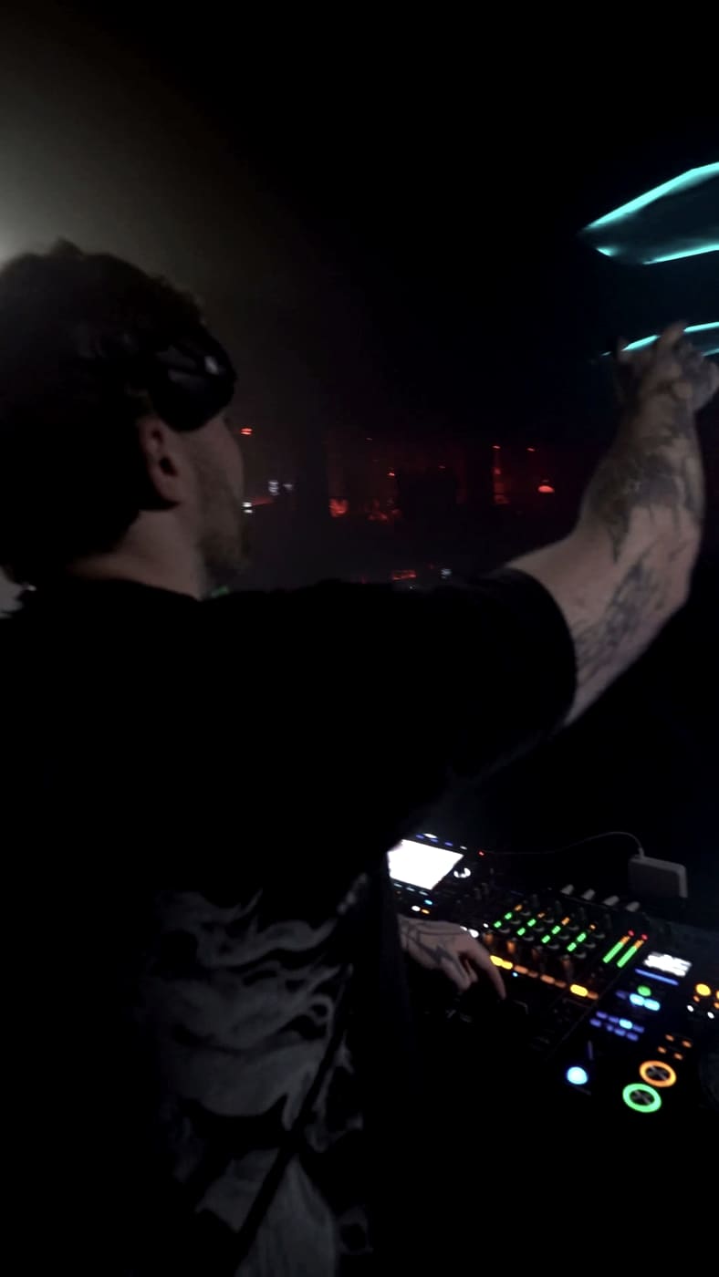 TWONSKi at the decks at Echostage, one arm raised over a red-lit arena